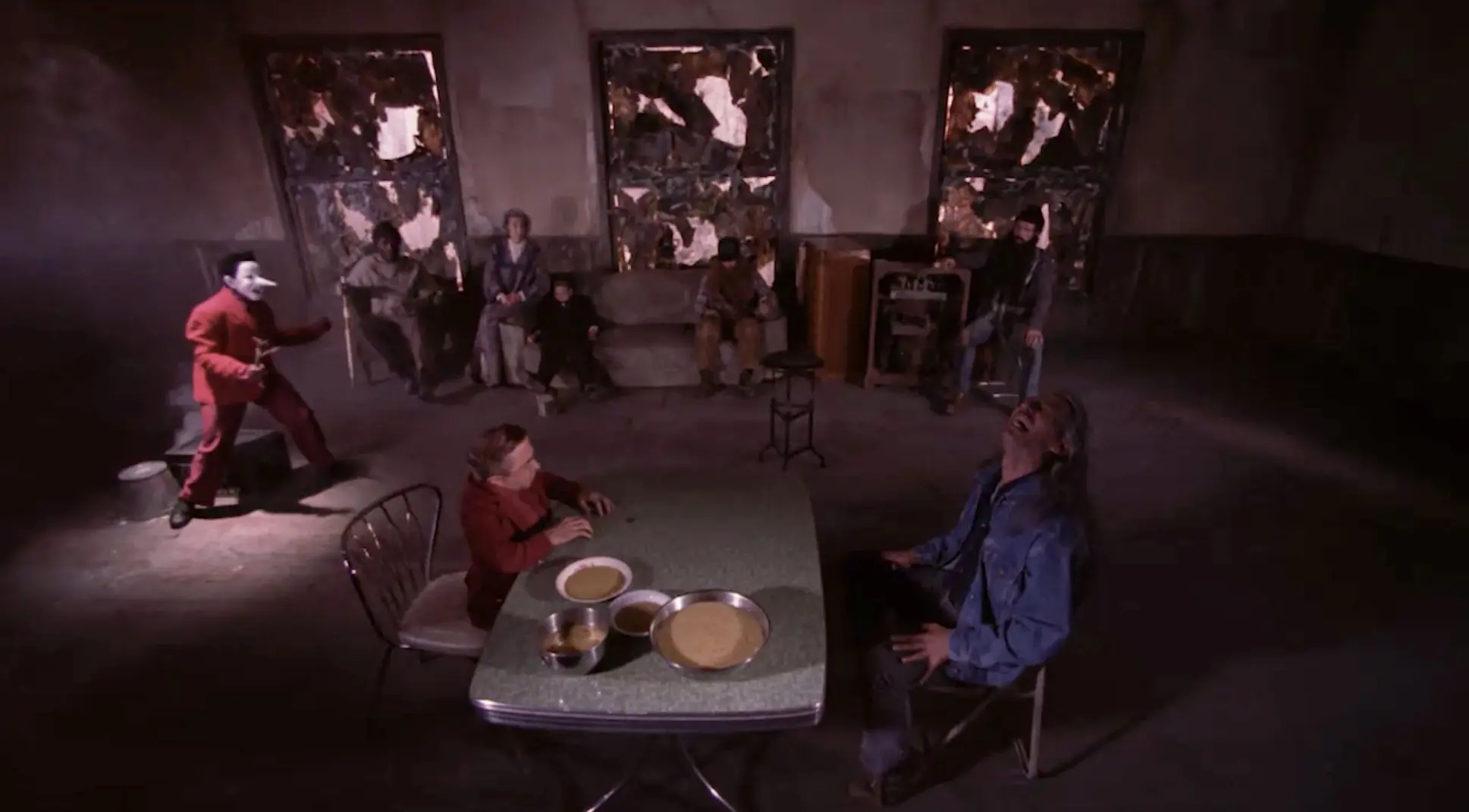 A screenshort from Twin Peaks Fire Walks With Me.

There are several characters sitting and standing in a run down room.