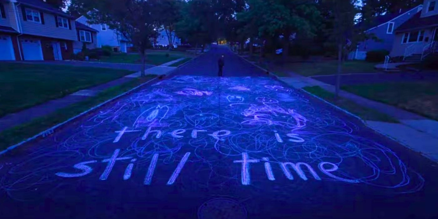 the screenshot from I Saw the TV Glow that reads "there is still time" written in chalk on the street
