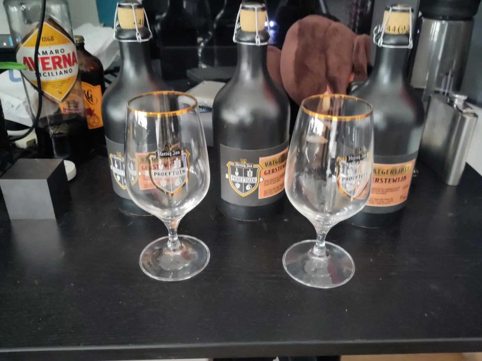 Three bottles of Hertog Jan proeftuin vatgerijpte gerstwijn and two glass proeftuin glasses.