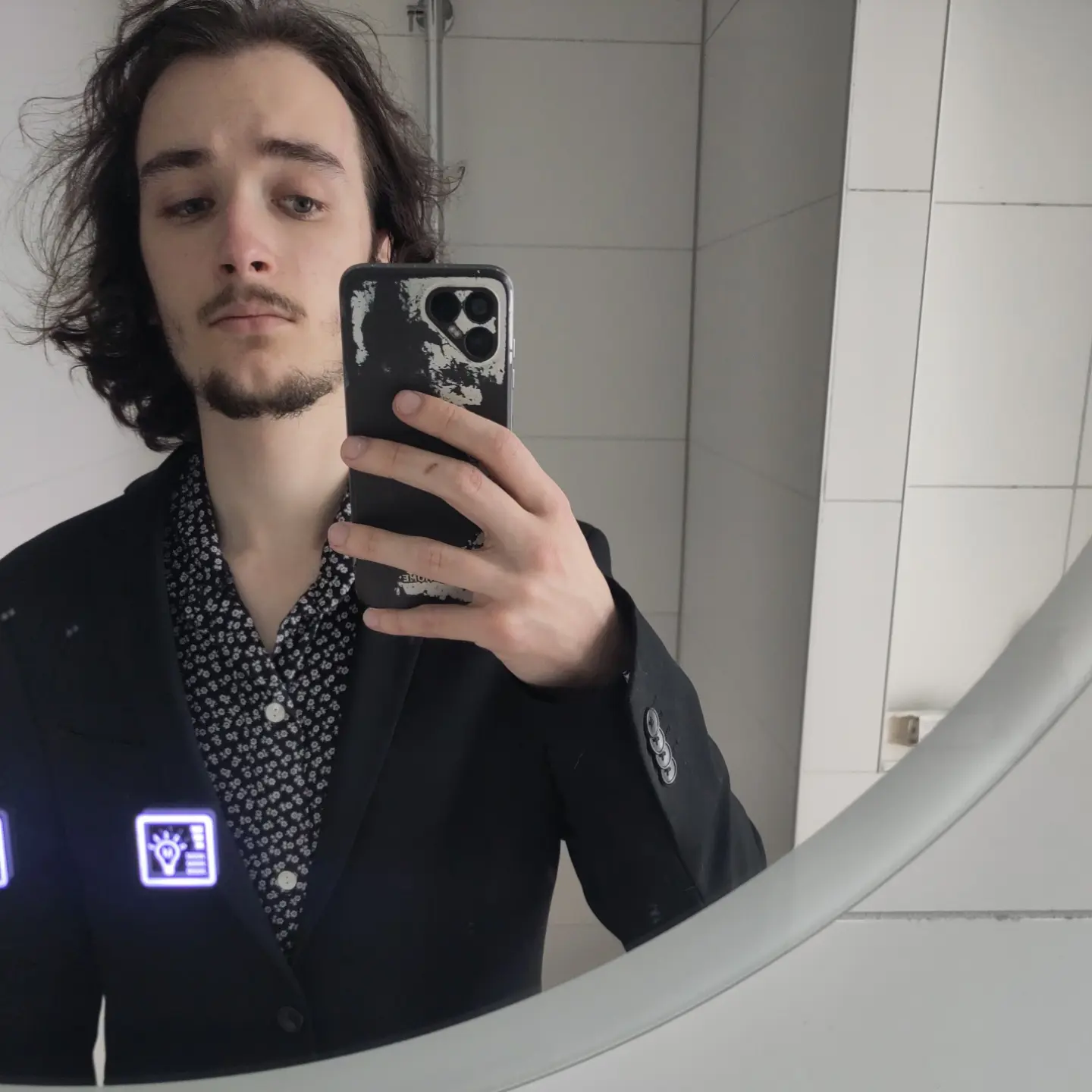 A mirror selfie of me wearing a suit jacket and a black blouse with small white flowers on it.