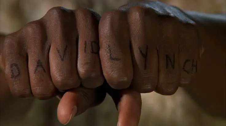 Still from the film Cecil B. Demented showing a knuckle tattoo that says D A V ID L Y N CH